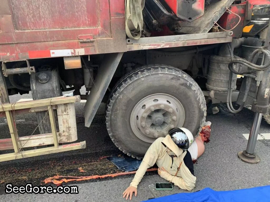 Mujer haciendo tranquilamente su última llamada telefónica bajo un neumático de camión.webp